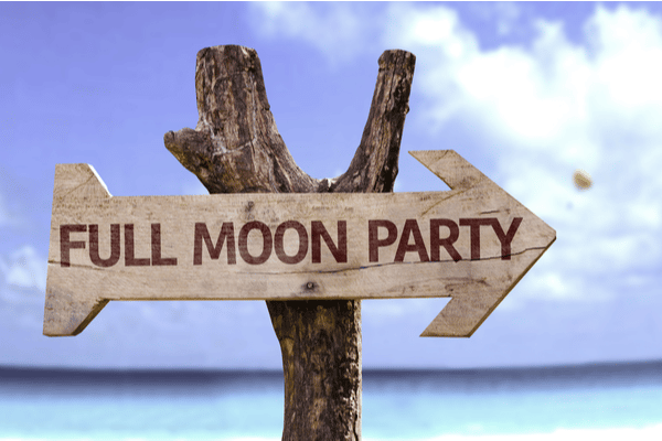a wooden sign leading along the beach to the full moon party