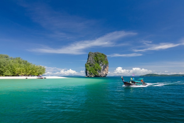 the stunning Ko Poda with a speedboat flashing past in the foreground and a unique rock formation in the background