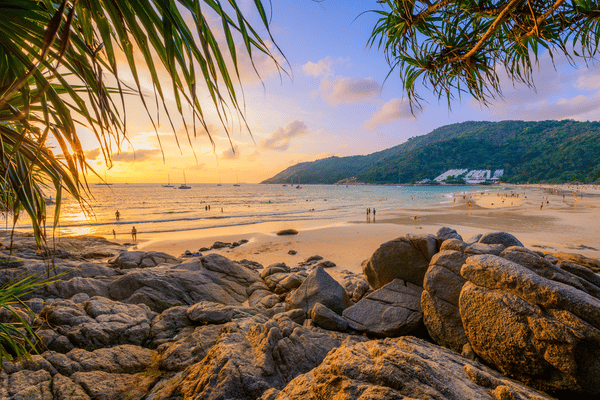 beach view of Nai Harn with the sun setting in the background