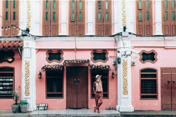 a blonde woman stands in front of a architecturally beautiful building in Phuket City