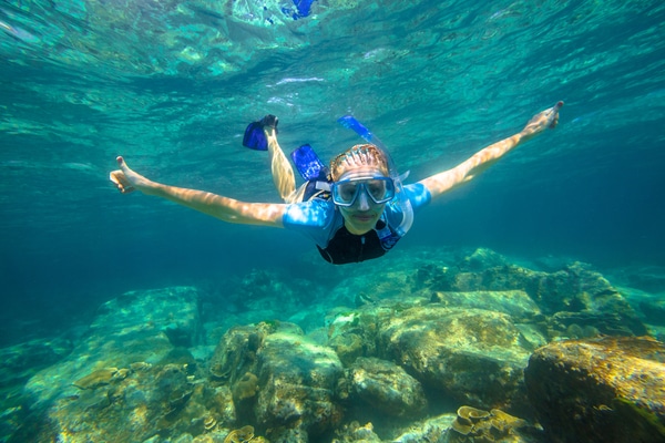 a young white woman snorkeling in the shallows along banana beach