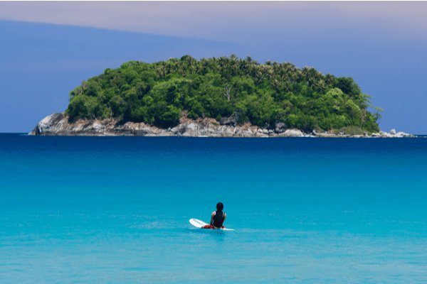 a female surfer in kata beach looking out towards the rock island