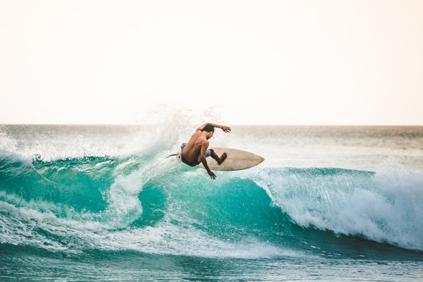 a shirtless man rides a wave in Phuket, Thailand