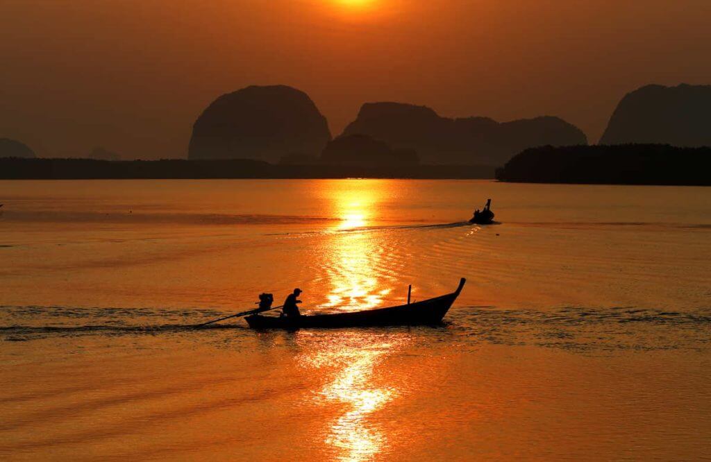 canoes in the sunset waters of phang nga bay
