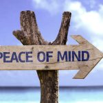 Wooden sign with the phrase 'Peace of Mind' on a beach.