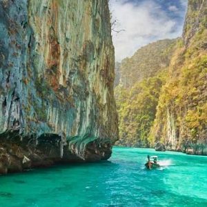 a boat traverses the crystal clear waters as part of a Phi Phi Island tour.