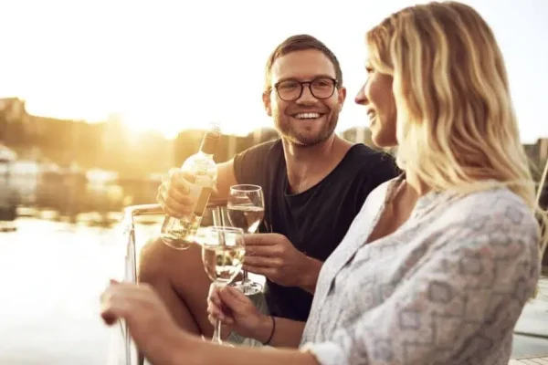 a white man with glasses and his blond partner enjoy a glass of wine on a Phuket boat tour