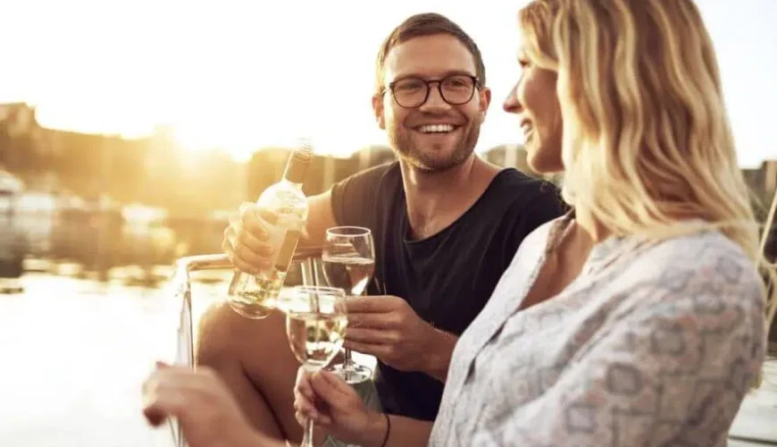 a white man with glasses and his blond partner enjoy a glass of wine on a Phuket boat tour
