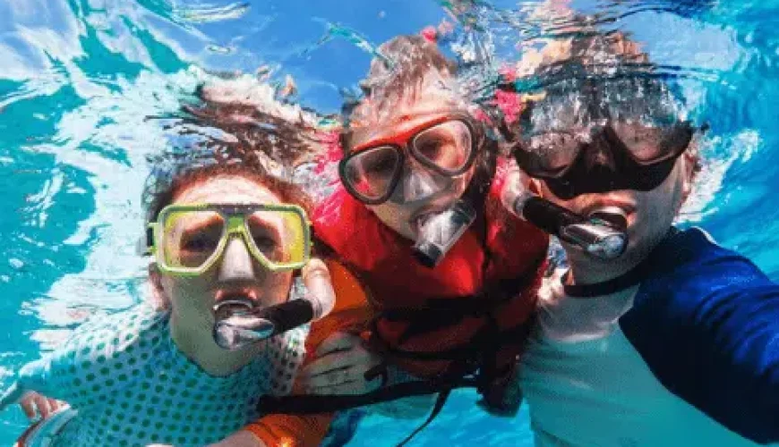 Three individuals wearing snorkeling gear exploring underwater marine life