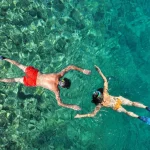 a male and female couple embracing the experience of snorkeling in phuket at the phi phi islands