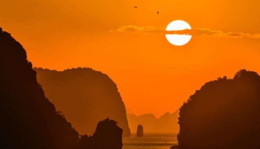 an image of the sun setting between two limestone karst rock formations about one of our sunset cruises in Phuket.