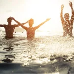 three people swimming in the beautiful beach off coconut island