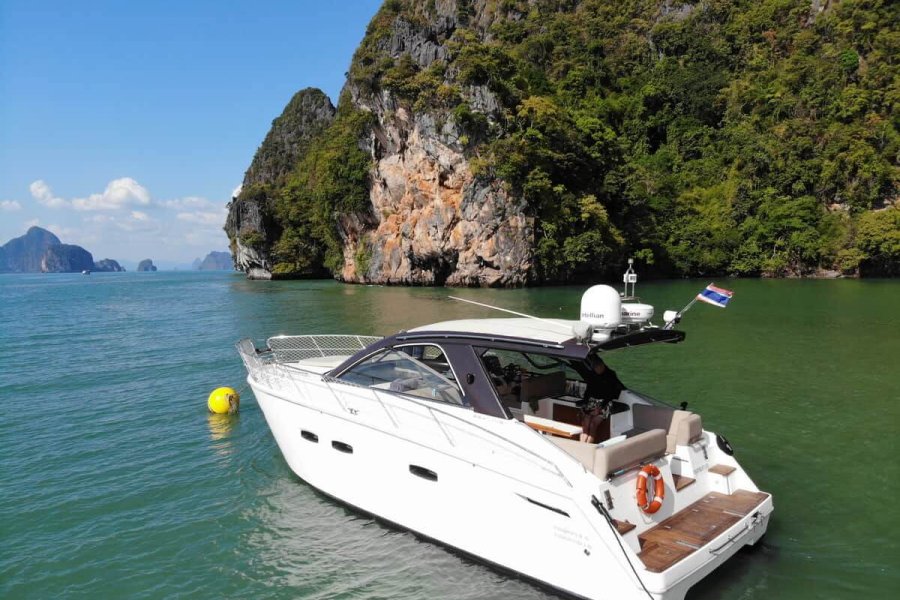 Luxury motor yacht in clear blue water near a limestone cliff 