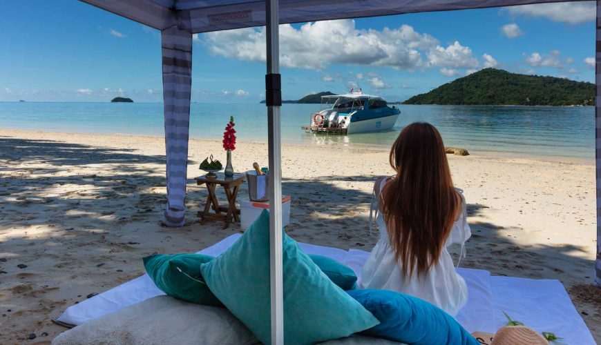 A woman on the beach taking in the view of the Simba Sea Trips speedboat in the beautifully clear water.