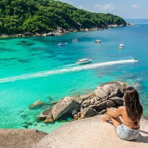 a white woman sits on a rock overlooking the crystal blue waters at Similan Islands