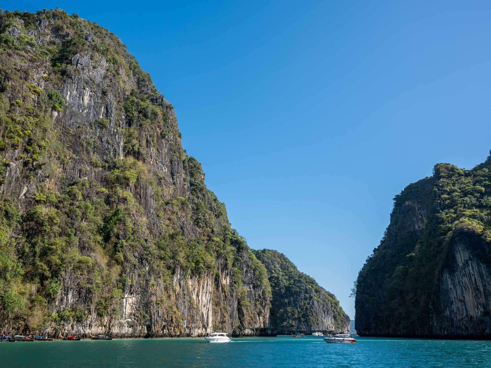 Boats sitting inside Pileh Lagoon's emerald water in the early morning, Phi Phi Leh