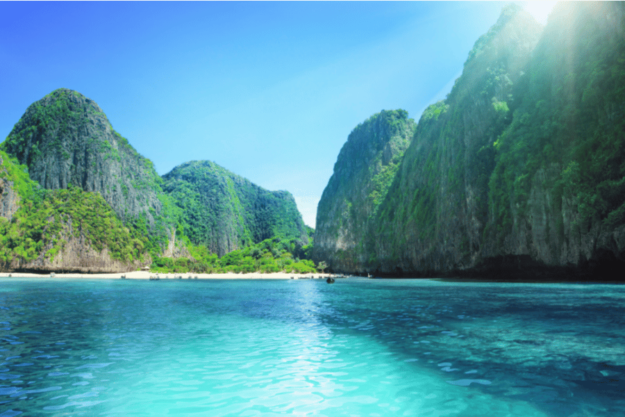 Maya Bay tropical bay with towering limestone cliffs covered in lush green vegetation.