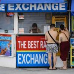 Two men exchanging currency at a money exchange counter in Phuket, Thailand