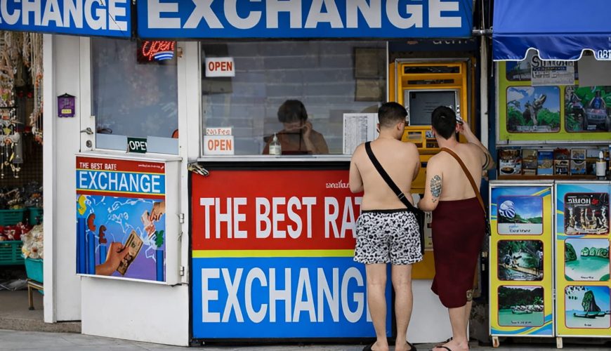 Two men exchanging currency at a money exchange counter in Phuket, Thailand
