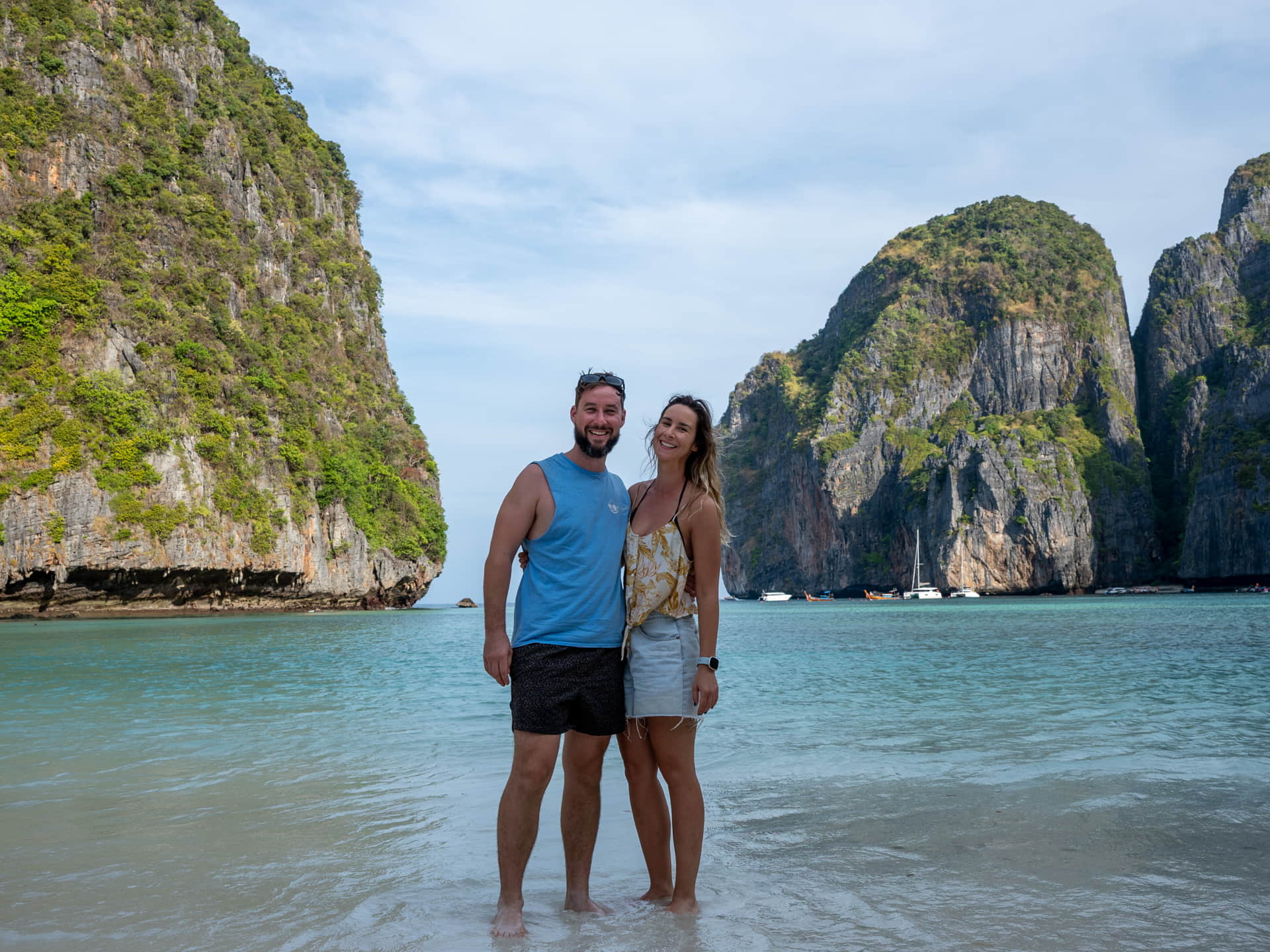 Phuket boat trips passing towering limestone cliffs and turquoise water on a sunrise cruise to the Phi Phi Islands.

