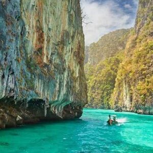 a boat traverses the crystal clear waters as part of a Phi Phi Island tour.