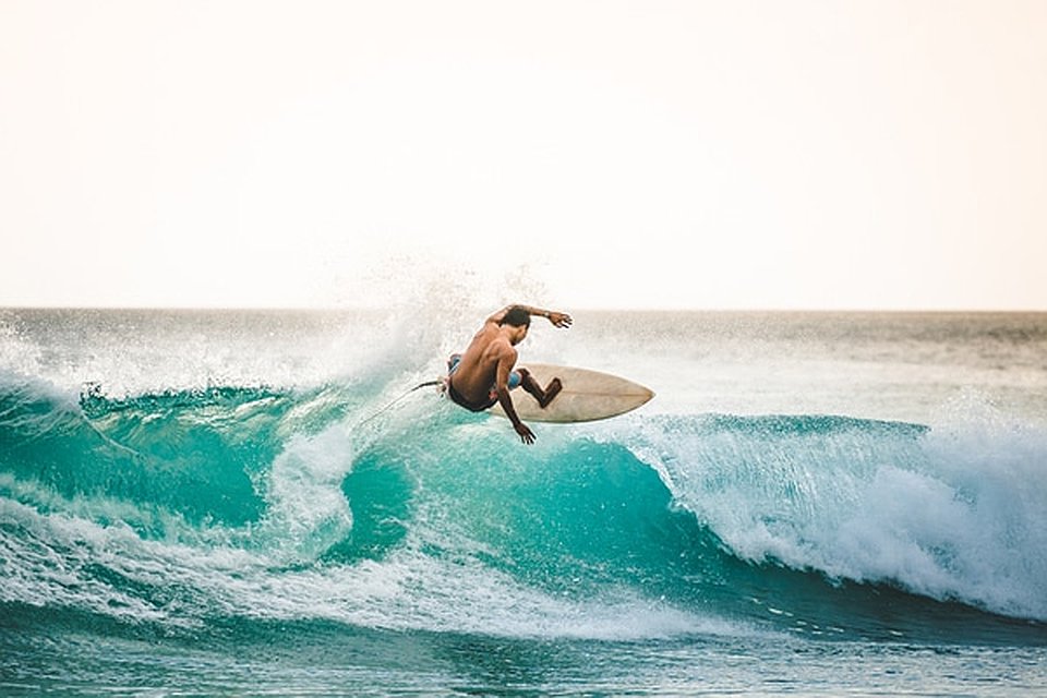 a shirtless man rides a wave in Phuket, Thailand